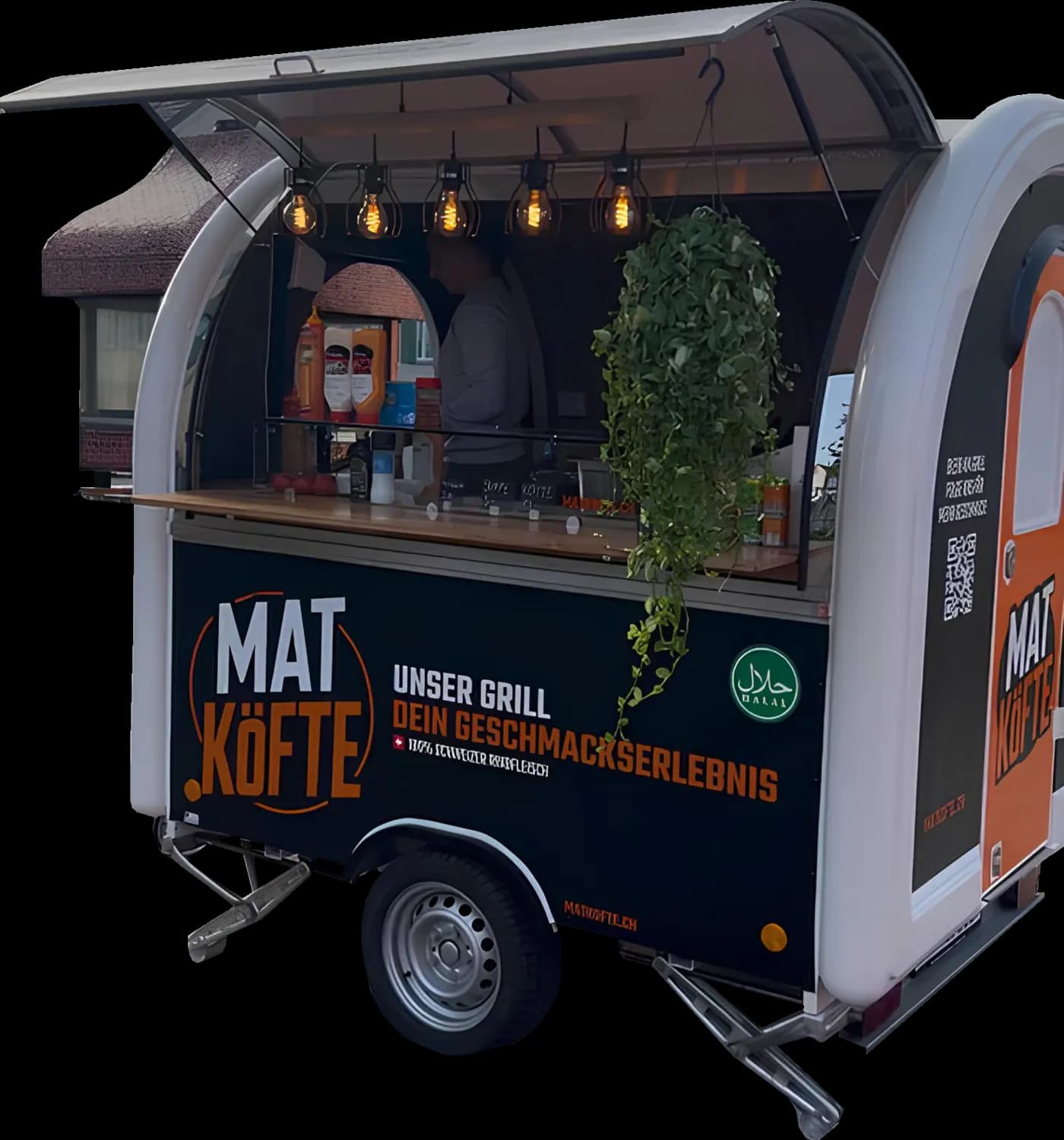 Der schwarz-orange MAT Köfte Verkaufsanhänger mit geöffneter Klappe und warmem Licht